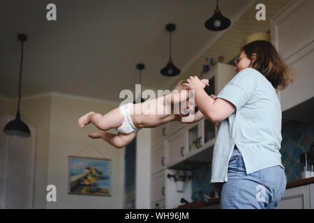 Mutter spielt mit ihrem kleinen Sohn in der Küche Stockfoto
