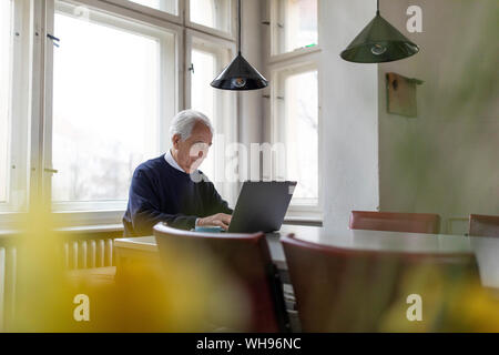 Älterer Mann mit Laptop auf dem Tisch zu Hause Stockfoto