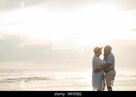 Senior Paar ständigen Gesicht am Strand zu Gesicht von Sonnenuntergang, Liepaja, Lettland Stockfoto