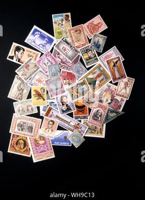 Eine Reihe von Briefmarken aus der ganzen Welt zufällig in einem Haufen gestapelt auf einem schwarzen Hintergrund. Stockfoto