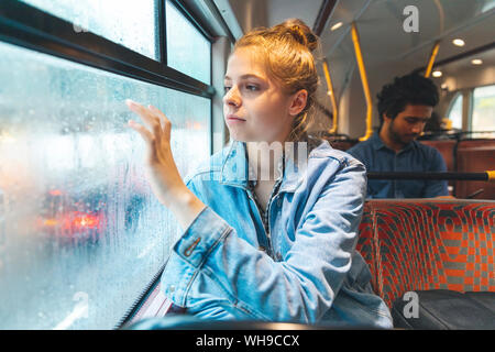 Junge Frau im Bus schreiben auf beschlagene Fensterscheibe mit dem Finger, London, UK Stockfoto