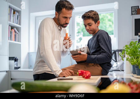 Vater und mit Tablet und Kochen in der Küche zu Hause zusammen Sohn Stockfoto