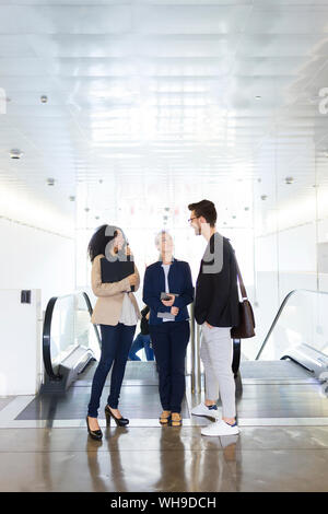Junge Unternehmen, die Menschen sprechen auf einer Rolltreppe Stockfoto