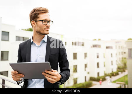 Geschäftsmann mit Tablet stehen auf Balkon in einem Entwicklungsbereich Stockfoto