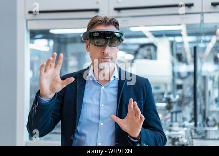 Unternehmer tragen AR-Gläser in ein modernes Werk Stockfoto