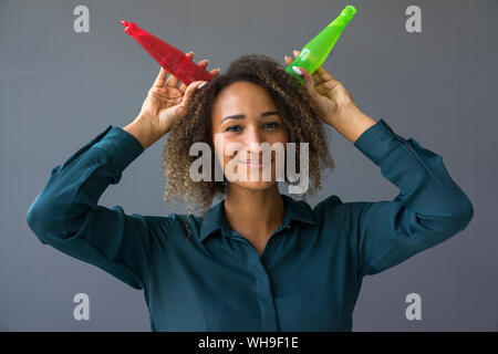 Portrait von lächelnden jungen Frau mit zwei plastikflaschen auf dem Kopf Stockfoto