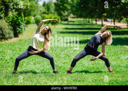 Reife frau yoga mit ihrer Tochter in einem Park Stockfoto