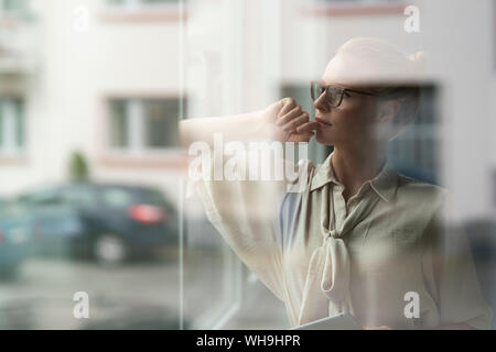 Nachdenkliche junge geschäftsfrau Blick aus Fenster Stockfoto