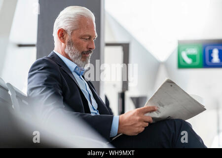 Reifen Geschäftsmann im Wartebereich lesen Zeitung sitzen Stockfoto