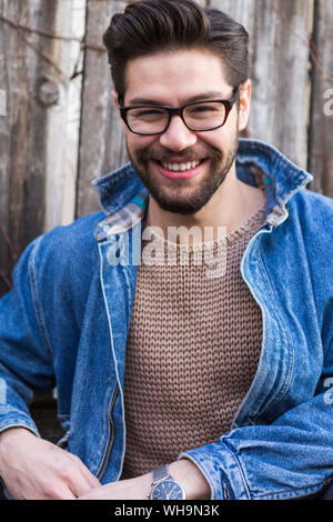 Portrait von lachenden jungen Mann mit Brille und Jeansjacke Stockfoto