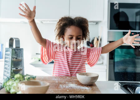 Mädchen spielen mit geriebenem Käse in der Küche Stockfoto