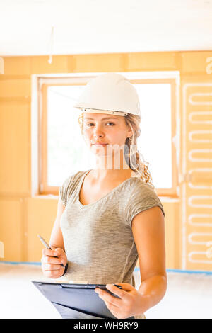 Porträt einer selbstbewussten jungen Frau, die in einem neuen Holzhaus Stockfoto