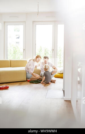 Glückliche Familie mit einem Sohn spielen im Wohnzimmer ihrer neuen Heimat Stockfoto