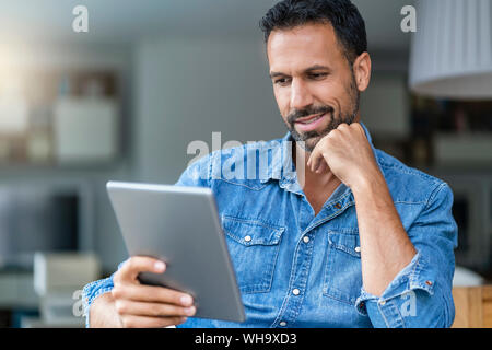 Lächelnder Mann mit Tablette zu Hause Stockfoto