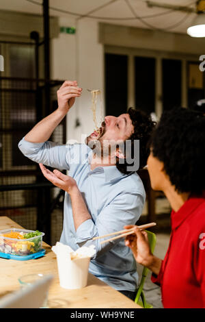 Geschäftsfrau aufpassen Kollegen Essen Nudeln während der Mittagspause Stockfoto