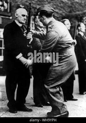 WW2: die Mitglieder des House of Lords und die Commons werden jetzt durch ihre Schritte als Mitglieder der örtlichen Verteidigung Freiwillige in der Spielplatz der Westminster School. Foto: Dr. Jocelyn Perkins, Sacrist zur Westminster Abbey, der ein L.D.V gesehen werden in Rifle Bohren von einem leitenden L.D.V. Mitglied angewiesen. Stockfoto