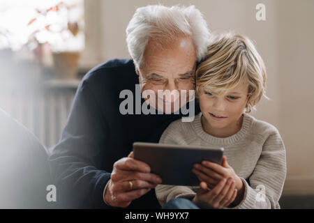 Großvater und Enkel mit einer Tablette zu Hause Stockfoto