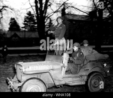 WW2: Lt Gen George S Patton Jr. dritten Armee, stehend in einem Jeep, begrüßt der Truppen der 2. Division, unter seinem Kommando, da sie Revue passieren, die während einer Inspektion Tour, im Armargh, Nordengland. Das sitzen in der Rückseite des Jeep ist Generalmajor Walter E Robertson, CG, 2. 3. April 1944. Stockfoto