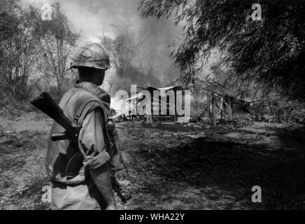Vietnam-krieg: Ein amerikanischer Soldat vor dem Brennen bleibt eines der Häuser in Phu Lam. Nach den Bränden unten gestorben, er und einer seiner Kameraden wurden durch das Dorf zu gehen, um sicher zu stellen, dass kein Viet Cong fighters in Tunneln unter den Häusern verborgen wurden. 1968 Stockfoto