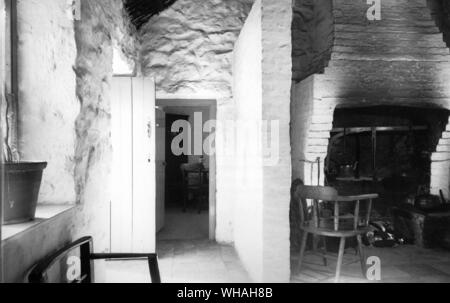 Küche Innenraum im Bauernhaus aus corradreenan West Gemeinde, County Fermanagh, jetzt an der Ulster Folk Museum. Die Tür von außen und die Küche Herd stehen im Einklang miteinander, so dass Sie durch den Pfosten Wand mit seinen kleinen Spion Fenster getrennt sind. Die erheblichen gemauerten Schornstein ist nicht original, sondern ersetzt eine Lehm verputzt Korbmacherwaren Schornstein, die gemauerten Schornstein gehört zu einer Reihe von Verbesserungen aus dem 19. Jahrhundert in das Haus integriert, ein weiterer die Fliesenboden Stockfoto