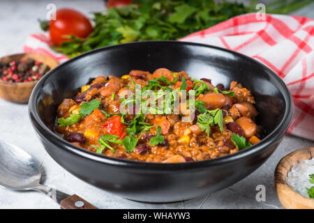 Chili con Carne aus Fleisch und Gemüse auf steinernen Tisch in der Nähe. Stockfoto