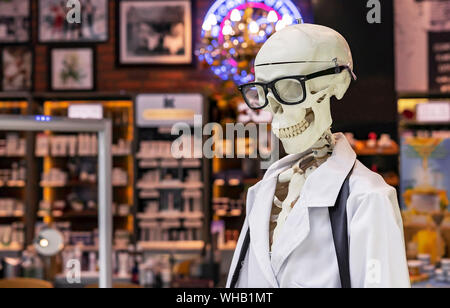 Menschliches Skelett in einem weißen medizinische Kleid und schwarzen Gläsern. Stockfoto