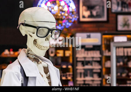 Menschliches Skelett in einem weißen medizinische Kleid und schwarzen Gläsern. Stockfoto