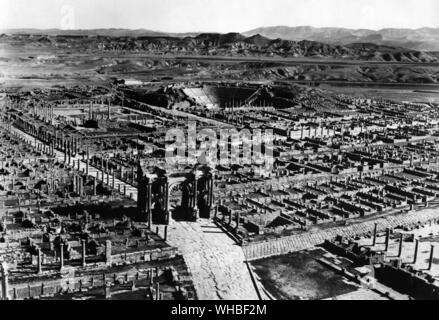 Timgad - Blick vom West End der Stadt zeigt der Bogen von Trajan, Forum und Theater, mit der aures Berge im Hintergrund - timgad war eine römische Kolonialstadt in Nordafrika, gegründet von Kaiser Trajan um 100 AD. Die Ruinen sind bemerkenswert, als eine der am besten erhaltenen Beispiele für die Grid Plan wie in der römischen Stadt Planung verwendet. Stockfoto