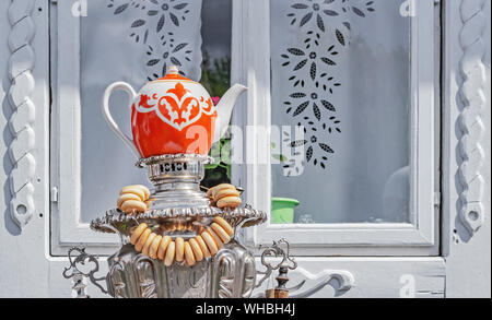 ? Eramic Teekanne steht auf einem samowar mit Bagels gegen einen weißen Holz- Fenster. Stockfoto