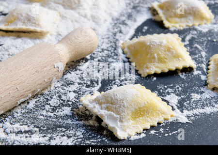 Frische rohe Ravioli mit Mehl auf einem dunklen Hintergrund. Prozess des klassischen italienischen Ravioli Stockfoto