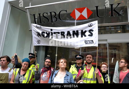 Die Demonstranten der Nordaufstand, die Teil der globalen Bewegung Extinction Rebellion sind, halten vor der HSBC Bank auf dem St. Anne's Square, Manchester, Großbritannien, ein Banner mit den „Exit Banks“. Die Demonstranten marschierten durch Manchester, großbritannien, und hielten am 2. September 2019 eine Reihe von Eindringinnen ab, um Maßnahmen gegen den Klimawandel zu fordern. Zu den Protestseiten gehörten die Barclays Bank, ein Primark-Geschäft und die HSBC Bank. Dies war der vierte Tag eines Protestes, der Deansgate, eine Hauptstraße im Zentrum von Manchester, blockierte. Stockfoto