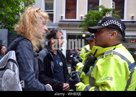 Polizisten sprechen Sie mit zwei Menschen, die eine Ihrer Hände, um das Fenster von der HSBC Bank als Northern Rebellion Demonstranten, Teil der globalen Bewegung Aussterben Rebellion geklebt, marschierten durch Manchester, UK, und hielt eine Reihe von sterben-ins für Maßnahmen gegen den Klimawandel zu drängen, am 2. September, 2019. Protest sites Barclays Bank, eine Primark store und HSBC Bank. Dieses war der vierte Tag des Protestes, der Deansgate, einer Hauptstraße im Zentrum von Manchester blockiert. Stockfoto