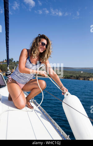 Junge attraktive Frau will fallen Bojen auf einem Segelboot auf den heißen Sommer Tag Stockfoto