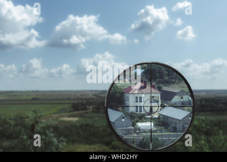 Eine vergrößerte Ansicht des Bereichs, in dem ein Haus im Tal in den optischen Anblick ist ein Sniper. Killer schaut in den optischen Anblick Stockfoto
