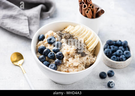 Haferflocken Haferbrei mit Früchten, Beeren und Chia Samen in weiße Schüssel. Konzept der gesunden Frühstück essen, saubere Essen, Gewichtsverlust Stockfoto