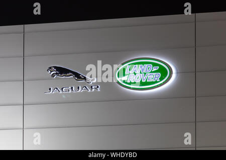 Die Logos von Jaguar und Land Rover leuchten nachts auf der Seite eines Händlerbetriebs. Stockfoto