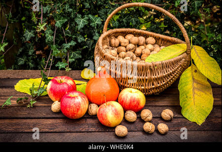 Herbst im Garten. Eine Komposition mit Äpfel, Kürbis und ein Korb mit Walnüssen Stockfoto