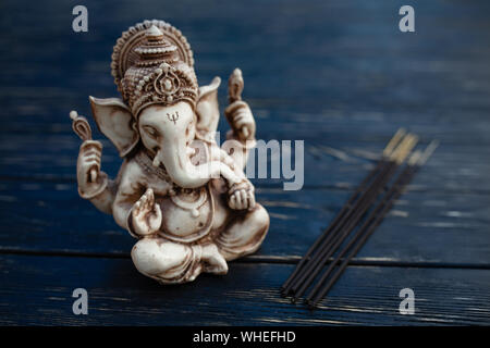 Hindu Gott Ganesh auf schwarzem Holz- Hintergrund. Statue auf Tabelle mit Sandelholz stick schließen oben mit Platz für Text kopieren Stockfoto