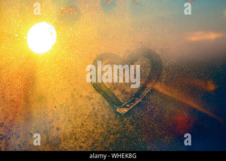 Atemberaubende vintage Orange sunrise Licht mit Herz Liebe Inschrift auf gefrorenen Fenster Glas. Soft Focus. Hintergrund mit kopieren. Stockfoto