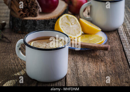 Heißen Tee mit Zitrone, Scheiben, Herbst und Winter gemütlich trinken in ländlichen Becher auf rustikalen Holztisch Stockfoto