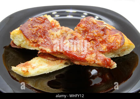 Pizza Schnitten auf einer schwarzen Platte. Pizza auf schwarzem Teller. Stockfoto