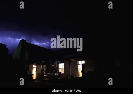 Schöne Aufnahme eines Hauses mit Licht und Blitz In einem dunklen Himmel im Hintergrund Stockfoto