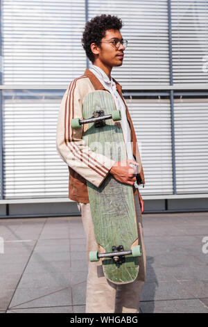 Skateboarder steht mit seinem Skateboard in der Stadt Stockfoto