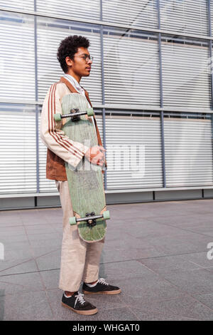 Skateboarder steht mit seinem Skateboard in der Stadt Stockfoto