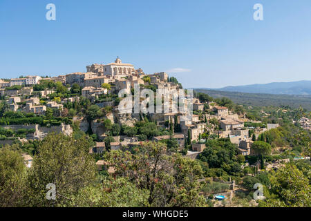 Gordes schönen alten Dorf mit pastellfarbenen Gebäuden auf dem Hügel, umgeben von Bergen, beliebtes Touristenziel in der Provence, Frankreich Stockfoto