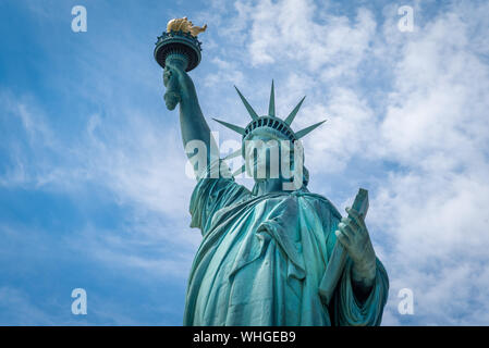 Schuss der Freiheitsstatue in New York City, USA. Der Schuß wird während ein schöner sonniger Tag mit blauem Himmel und weißen Wolken im Hintergrund Stockfoto