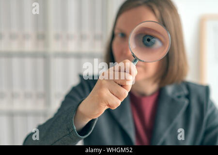 Geschäftsfrau mit Lupe, die finanzielle Überwachung, Prüfung und Bewertung von Jahresabschlüssen. Stockfoto