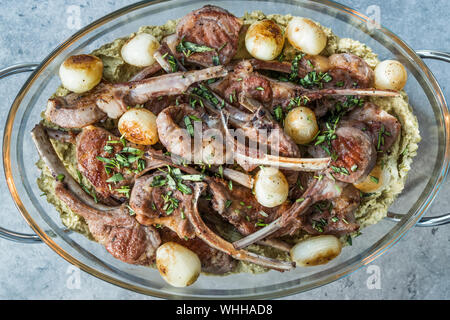 Lammkoteletts mit Schalotten, grüne Erbse Hummus und Frische Thymianblättchen diente im Großen Glas Fach Platte. Organisches Fleisch essen. Stockfoto