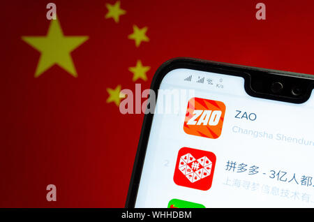 ZAO App Symbol auf dem Bildschirm des Smartphones und den unscharfen Flagge von China auf dem Bildschirm hinter sich. Zao ist derzeit einer Zahl eine unterhaltsame App in China. Stockfoto