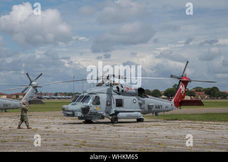 Ein Seemann leitet ein U.S. Navy MH-60R Sea Hawk Hubschrauber nach Maxwell Air Force Base, Alabama anreisen, von der Naval Air Station Jacksonville und Naval Station Mayport, Florida, Sept. 1, 2019. Die Hubschrauber vom Jacksonville Bereich im Vorfeld des Hurrikans Dorian evakuiert. Zusätzlich zu den Hubschraubern, Maxwell AFB dient als Incident Support Base für Federal Emergency Management Agency und Defense Logistics Agency Personal und Ausrüstung. (U.S. Air Force Foto von Billy Birchfield) Stockfoto